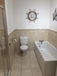 a bathroom with a toilet and a bath tub and a boat on the wall at Cederee in Rhyl