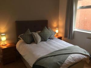 a bedroom with a bed with pillows and two lamps at Cederee in Rhyl