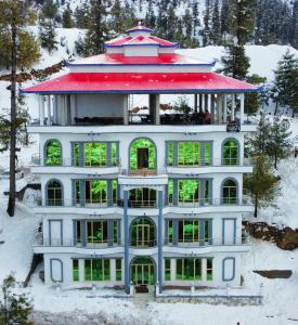 een groot gebouw met een rood dak in de sneeuw bij Al-Sadiq Hotel & Restaurant Malam Jabba Swat in Swat