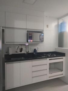 une cuisine avec des armoires blanches et un comptoir noir dans l'établissement Apto Ventano, à Campos dos Goytacazes