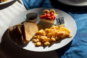 a plate of breakfast food with eggs toast and fruit at Roxy's Bed & Breakfast in Boca Chica