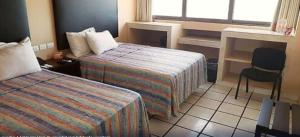 a hotel room with two beds and a desk and a chair at Hotel Terrasol in Coatzacoalcos