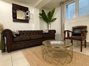 a living room with a brown couch and a table at Le Faubourg des Trois Provinces, Zoo de Beauval in Noyers-sur-Cher