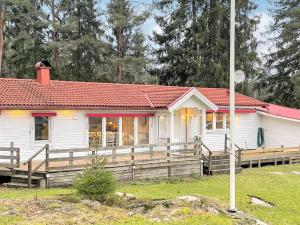 una pequeña casa blanca con techo rojo en Holiday home PRÄSSEBO II, en Eckerud