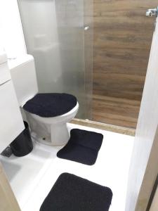 une salle de bain avec WC avec douche et deux tapis noirs dans l'établissement Apto Ventano, à Campos dos Goytacazes 16 autres photos