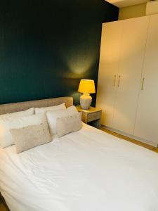 a bedroom with a white bed with a green wall at DMN City at Merensky Apartment in Windhoek