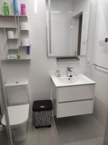 a white bathroom with a sink and a mirror at Apartamento playa de Chancelas, Pontevedra in Combarro