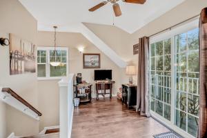 a living room with a ceiling fan and large windows at Inviting waterfront cottage with balcony, firepit, marsh views, & washer/dryer in Fernandina Beach