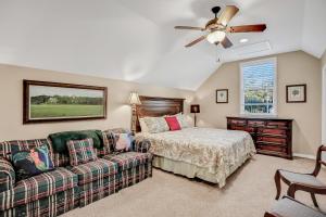 a bedroom with a bed and a couch and a ceiling fan at Inviting waterfront cottage with balcony, firepit, marsh views, & washer/dryer in Fernandina Beach