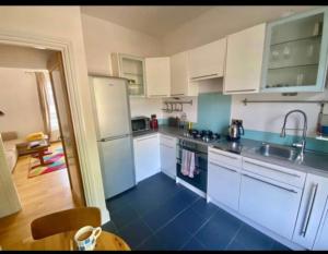 una cucina con armadi bianchi e piano di lavoro blu di Fab location 2 bed garden flat camden a Londra