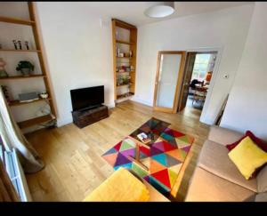 een woonkamer met een kleurrijke tafel op een houten vloer bij Fab location 2 bed garden flat camden in Londen