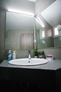 La salle de bains est pourvue d'un lavabo et d'un grand miroir. dans l'établissement Violet City Center Apartments, à Kavala