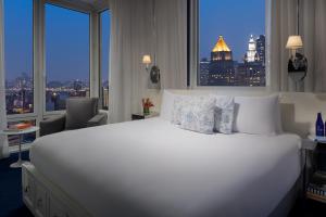 a large white bed in a hotel room with a window at NoMo SoHo in New York