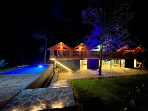a house at night with a swimming pool at PINE TREE Mazamitla Hotel Boutique & Cabañas in Mazamitla