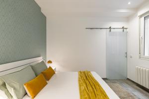 1 dormitorio con 1 cama blanca grande con almohadas amarillas en BNBHolder Relishing LA GRAN VIA, en Madrid