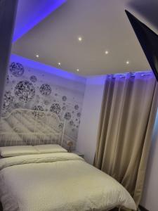 una camera da letto con letto bianco e illuminazione viola di Appartamento Diana ad Aosta