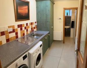 a kitchen with a sink and a washing machine at 3-Bedroom Cottage With Plenty Space 