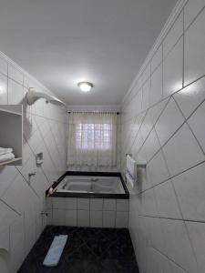 a bathroom with a bath tub and a window at Casa com piscina aconchegante e relaxante in Mongaguá