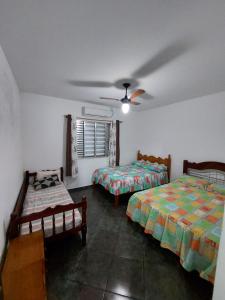 a bedroom with two beds and a ceiling fan at Casa com piscina aconchegante e relaxante in Mongaguá