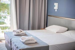 two beds in a hotel room with towels on them at Hotel Lumbarda in Lumbarda