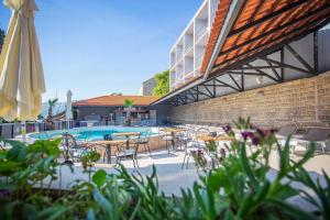 a pool with tables and chairs and an umbrella at Hotel Lumbarda in Lumbarda