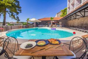 a table with food on it next to a swimming pool at Hotel Lumbarda in Lumbarda