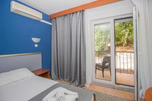 a bedroom with a bed and a window with a balcony at Hotel Lumbarda in Lumbarda