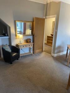 een woonkamer met een stoel, een tafel en een spiegel bij Horncliffe room only accommodation in Seahouses