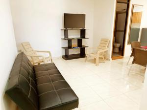 a living room with a couch and chairs and a television at Apartamentos Pitalito in Pitalito