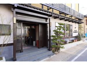 Kusatsu Onsen 326 Yamanoyu Hotel - Vacation STAY 10349v في كوساتسو: باب امامي لمبنى فيه شجرة بالخارج