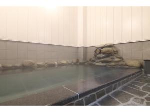 Una gran piscina de agua en una habitación con una pared de piedra. en Kusatsu Onsen 326 Yamanoyu Hotel - Vacation STAY 10349v en Kusatsu