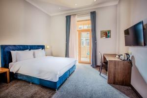 um quarto de hotel com uma cama, uma secretária e uma televisão em Alma Boutique Hotel em Tbilisi
