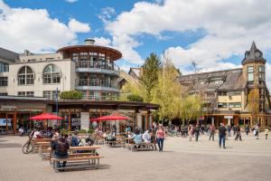 a group of people sitting on benches in a city street at Steps From The Village with Pool and Hot Tub by Harmony Whistler in Whistler