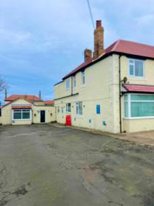 un estacionamiento vacío frente a un edificio blanco en Horncliffe room only accommodation, en Seahouses