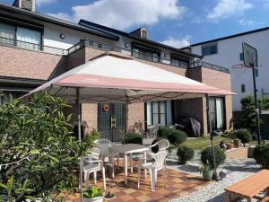 eine Terrasse mit einem Tisch und Stühlen unter einem Sonnenschirm in der Unterkunft MEILAN HOUSE - Vacation STAY 13804 in Osaka