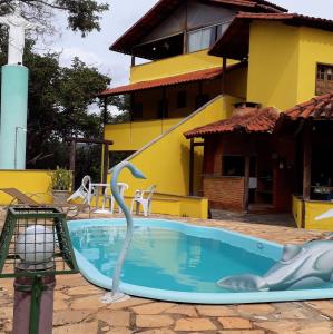 una piscina con una estatua de un delfín frente a una casa en Nova Pousada Sollaris - Coração da Serra do Cipó - MG, en Santana do Riacho