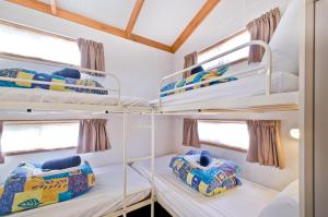 a room with three bunk beds in a boat at Warragul Gardens Holiday Park in Warragul
