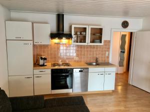 a kitchen with white cabinets and a stove top oven at Landhaus Klausner in Saalbach Hinterglemm