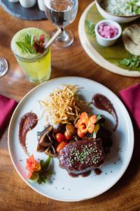 un plato de comida con carne y verduras en una mesa en Trogon Lodge, en San Gerardo de Dota