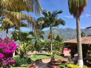 einen Garten mit Palmen und Blumen in einem Resort in der Unterkunft Finca Quinta San Antonio, Girardota, Antioquia in Girardota