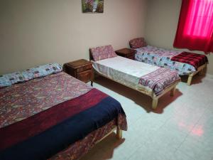 una habitación con 3 camas y una silla. en Casas Arnau en Termas de Río Hondo