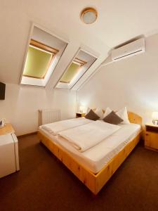 a bedroom with a large bed with two skylights at Sommer Panzió in Balatonföldvár