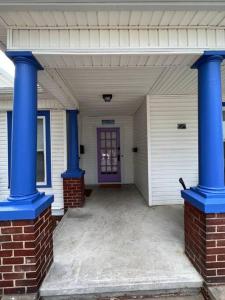 um alpendre com colunas azuis numa casa branca em The Purple Door apt in the heart of Radford city em Radford