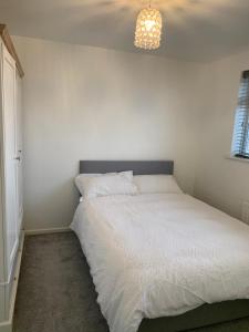 Adsa Guesthouse في Seacroft: سرير أبيض في غرفة نوم مع ثريا