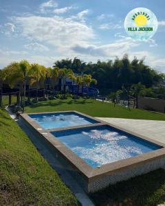 a swimming pool in a grassy area next to a park at Villa Jackson in La Tebaida
