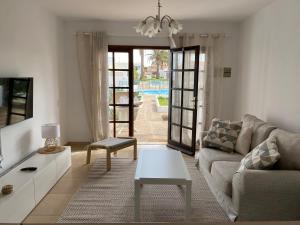 a living room with a couch and a table at Estrella Del Mar 8. 1 Bedroom Villa with Pool and Gardens 300 metres from the beach in Corralejo
