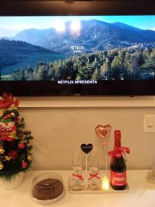 a table with a television and a bottle of wine and glasses at Suíte da Cris em Gramado in Gramado