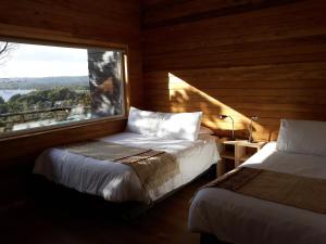 1 dormitorio con 2 camas y ventana grande en Huillín Lodge, en Chonchi
