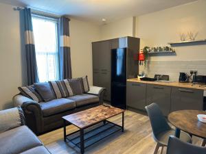 a living room with a couch and a refrigerator and a table at Bentinck Apartments in Newcastle upon Tyne