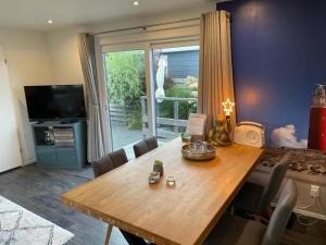 a dining room with a wooden table and a large window at Beachhouses Texel in De Koog